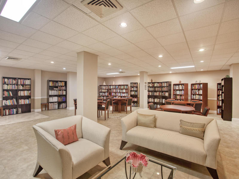 Private residents' library lounge at The Claridges with floor-to-ceiling bookshelves, reading tables, and lounge seating