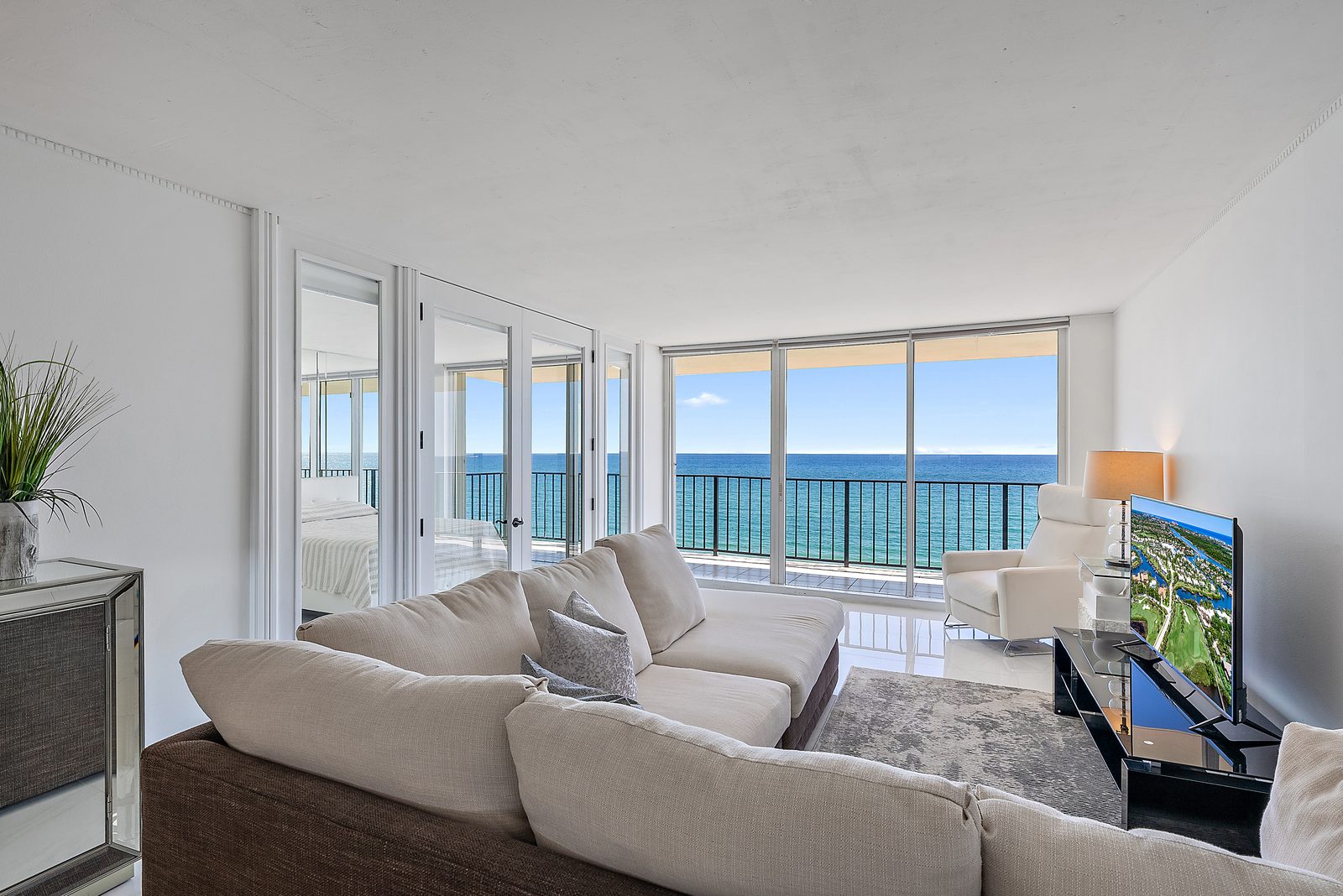 Living room at The Claridges Penthouse 802 with sectional sofa and French doors opening to direct oceanfront terrace